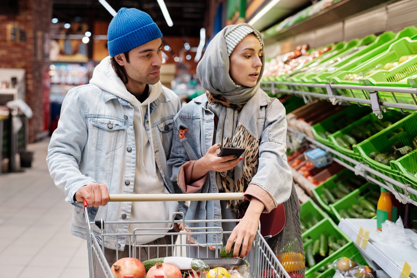 Dos personas con el carro en la sección de verduras de un supermercado